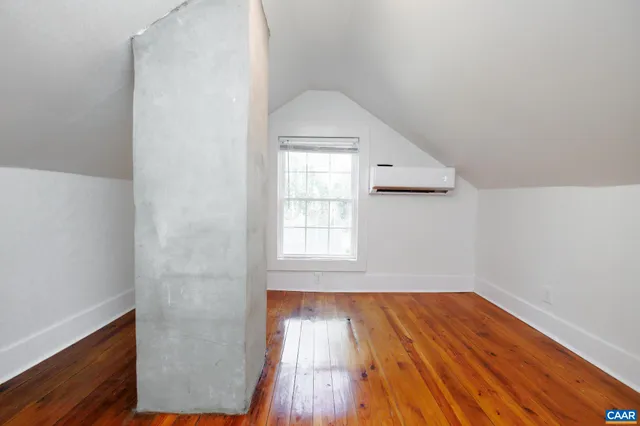 an empty room with wooden floor cabinet and windows
