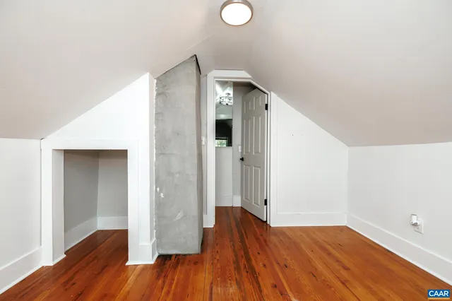an empty room with wooden floor and entrance