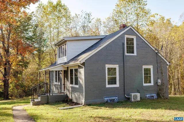 a front view of house with yard and trees in the background