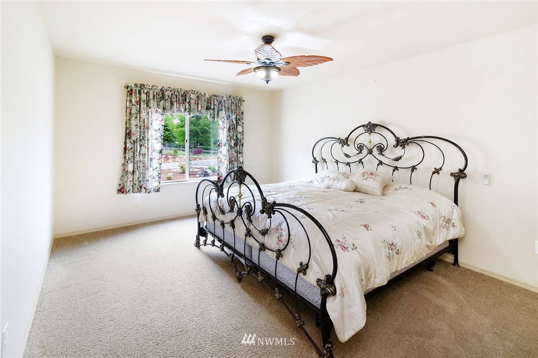 1450 Southeast Spruce Road Port Orchard, WA 98367 - Photo 17 of 40 a spacious bedroom with a bed a chandelier and a large window