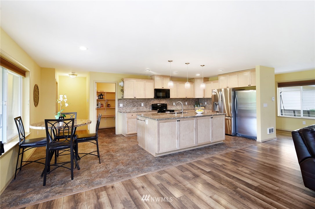 1450 Southeast Spruce Road Port Orchard, WA 98367 - Photo 5 of 40 a kitchen with stainless steel appliances kitchen island granite countertop a table chairs sink and cabinets