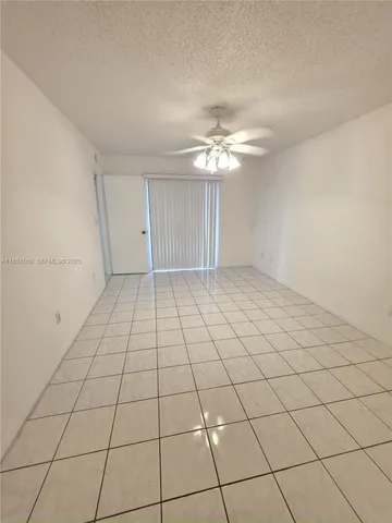 a view of an empty room and chandelier fan