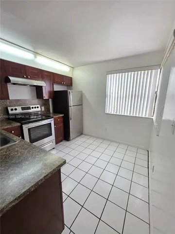 a kitchen with kitchen island granite countertop a stove a sink and a refrigerator