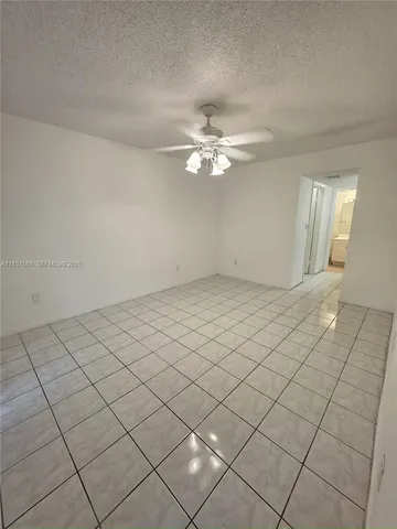 a view of an empty room and chandelier fan