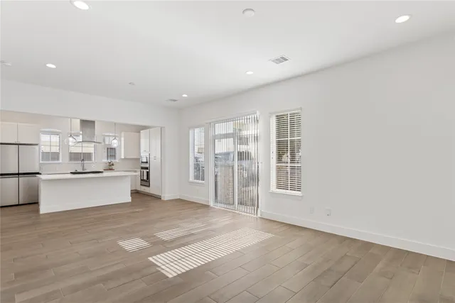 a large white kitchen with kitchen island a sink dishwasher a stove and a refrigerator with wooden floor