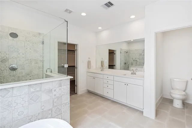 a spacious bathroom with a granite countertop sink a toilet a mirror and shower