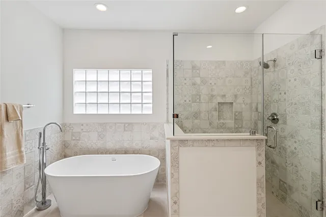 a bathroom with a white bath tub a shower and a sink