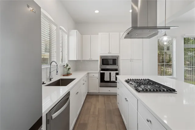 a kitchen with stainless steel appliances a sink a stove a refrigerator and cabinets