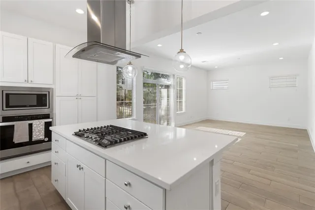 a kitchen with stainless steel appliances granite countertop a sink a stove a refrigerator cabinets and wooden floor