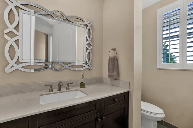 a bathroom with a granite countertop sink a toilet and a mirror