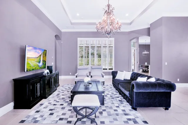 a living room with furniture a chandelier and a flat screen tv