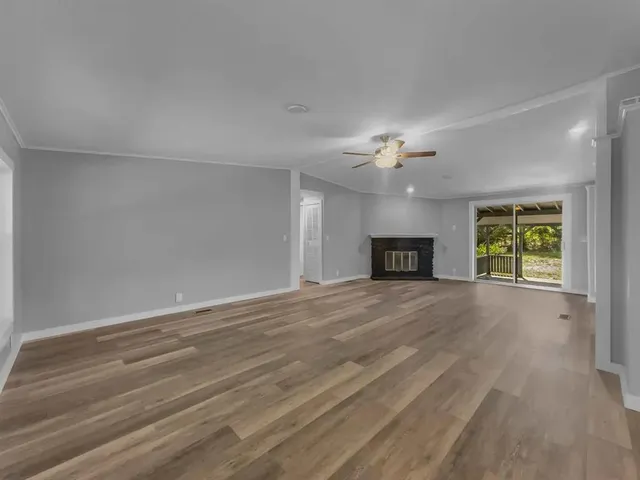 a view of an empty room with a window and a chandelier fan