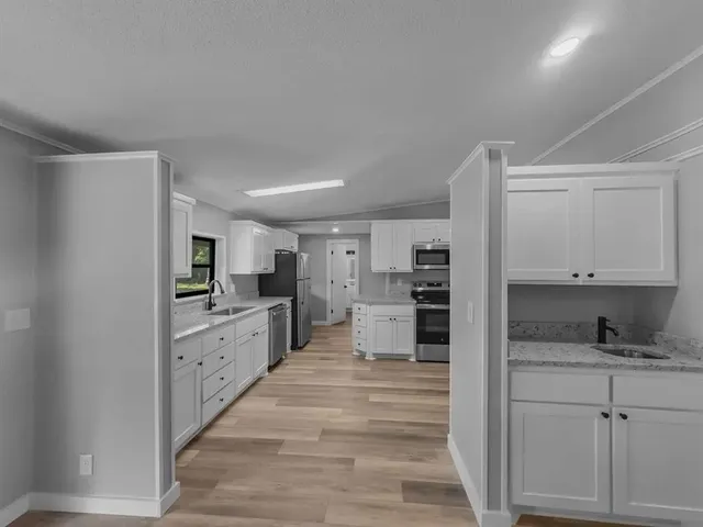 a kitchen with stainless steel appliances kitchen island granite countertop a refrigerator stove and sink