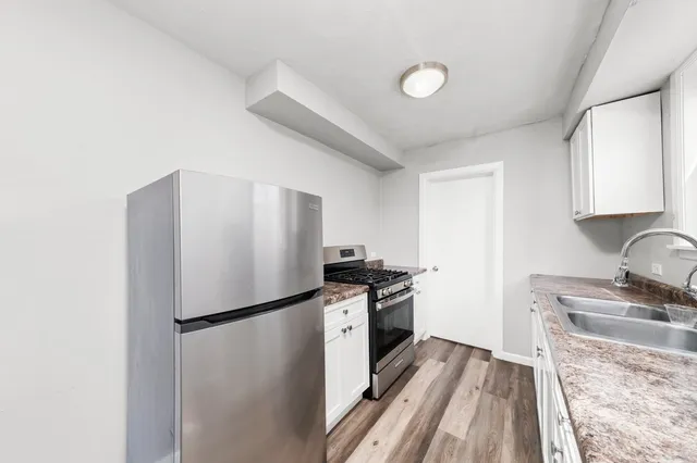 a kitchen with granite countertop a refrigerator stove and sink