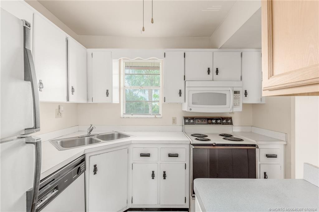 1999 Southwest Palm City Road, Unit G Stuart, FL 34994 - Photo 5 of 23 a kitchen with cabinets appliances a sink and a window
