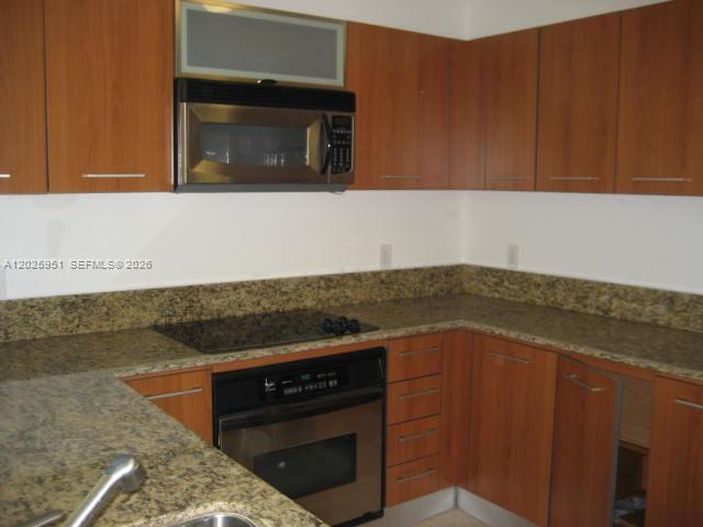 9066 Southwest 73rd Court, Unit 1802 Miami, FL 33156 - Photo 3 of 12 a kitchen with granite countertop cabinets and stove top oven