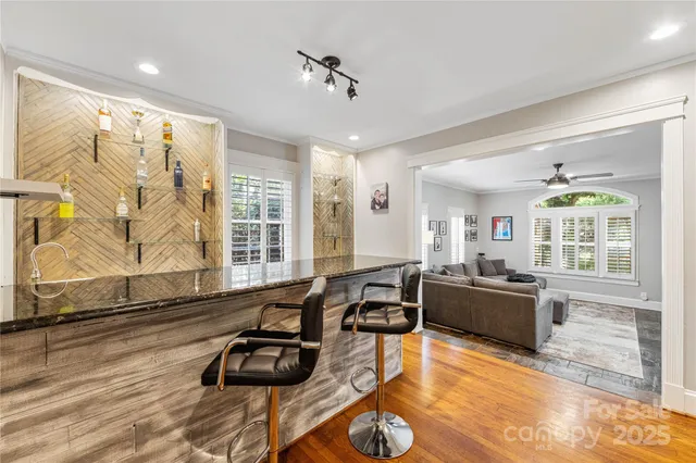 a living room with furniture hard wood floor and a floor to ceiling window