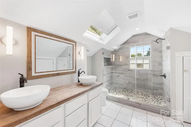a spacious bathroom with a granite countertop sink a toilet a mirror and shower