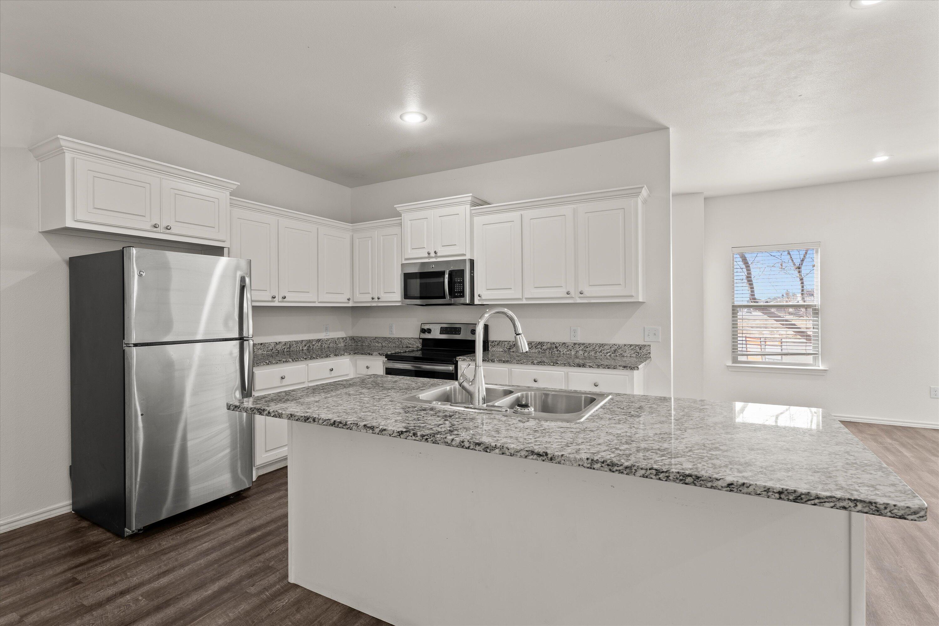 6908 21st Street Lubbock, TX 79407 - Photo 12 of 28 a kitchen with granite countertop a refrigerator a sink a stove a microwave and cabinets