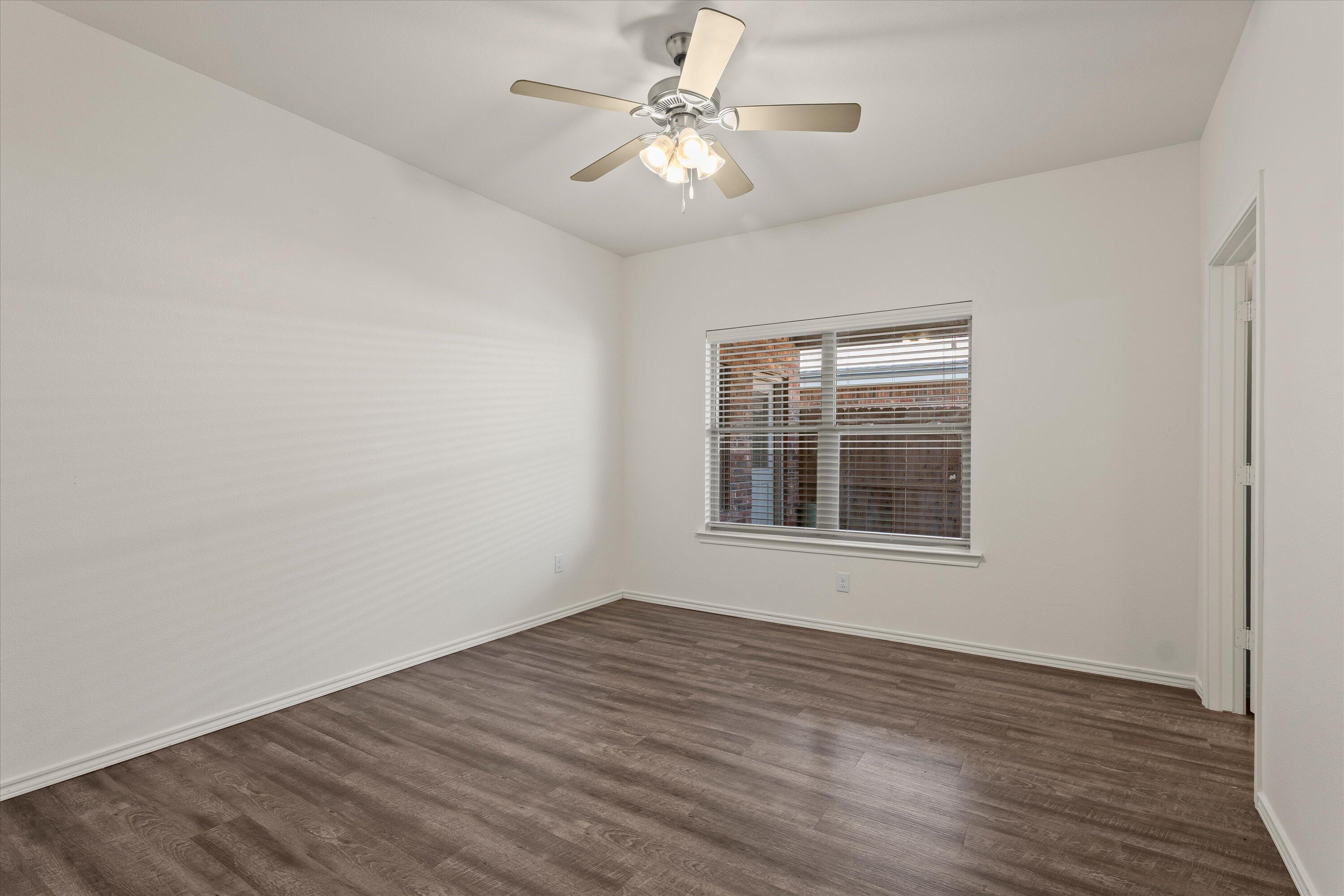 6908 21st Street Lubbock, TX 79407 - Photo 14 of 28 a view of an empty room with wooden floor and a window
