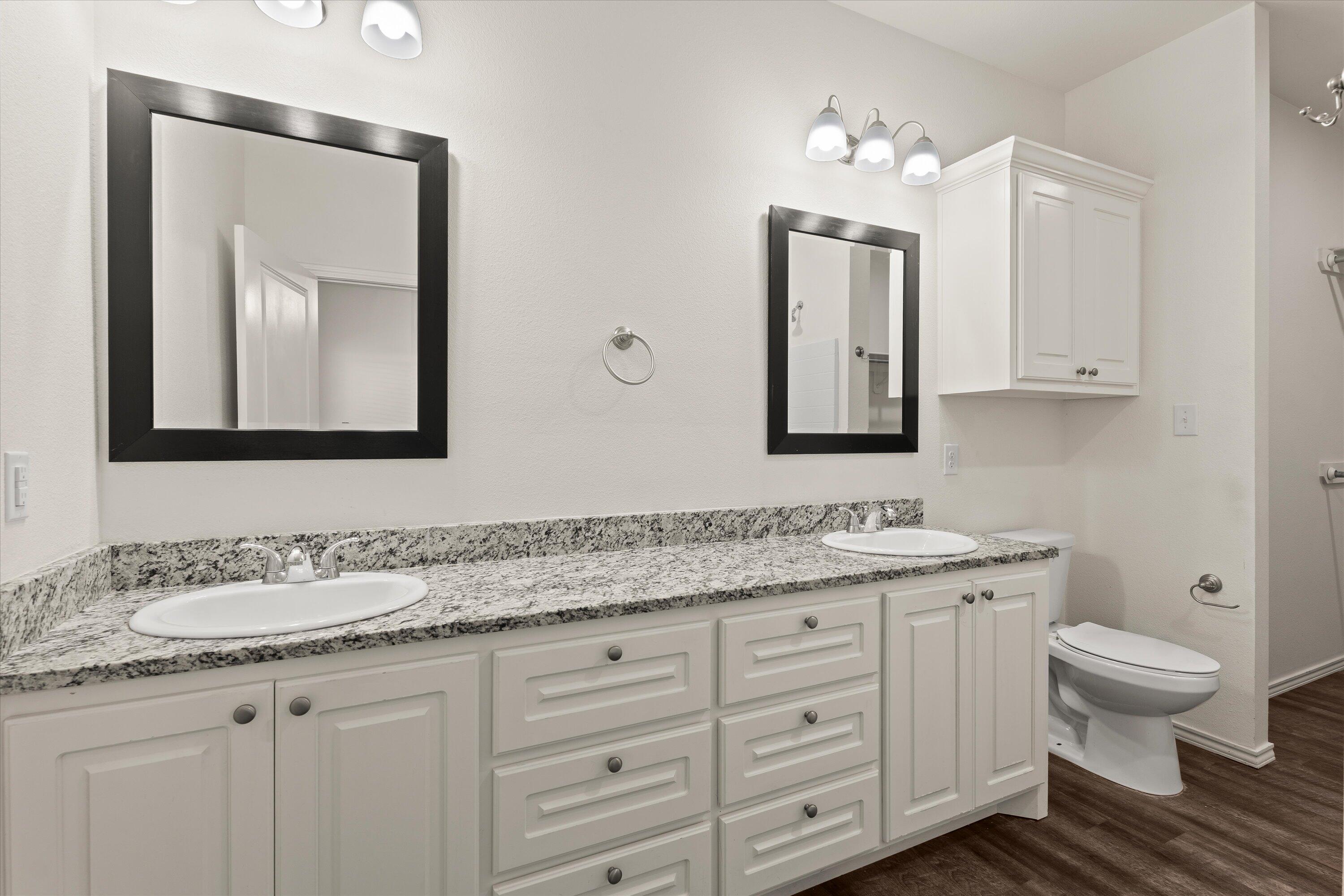 6908 21st Street Lubbock, TX 79407 - Photo 16 of 28 a bathroom with a granite countertop toilet sink and mirror