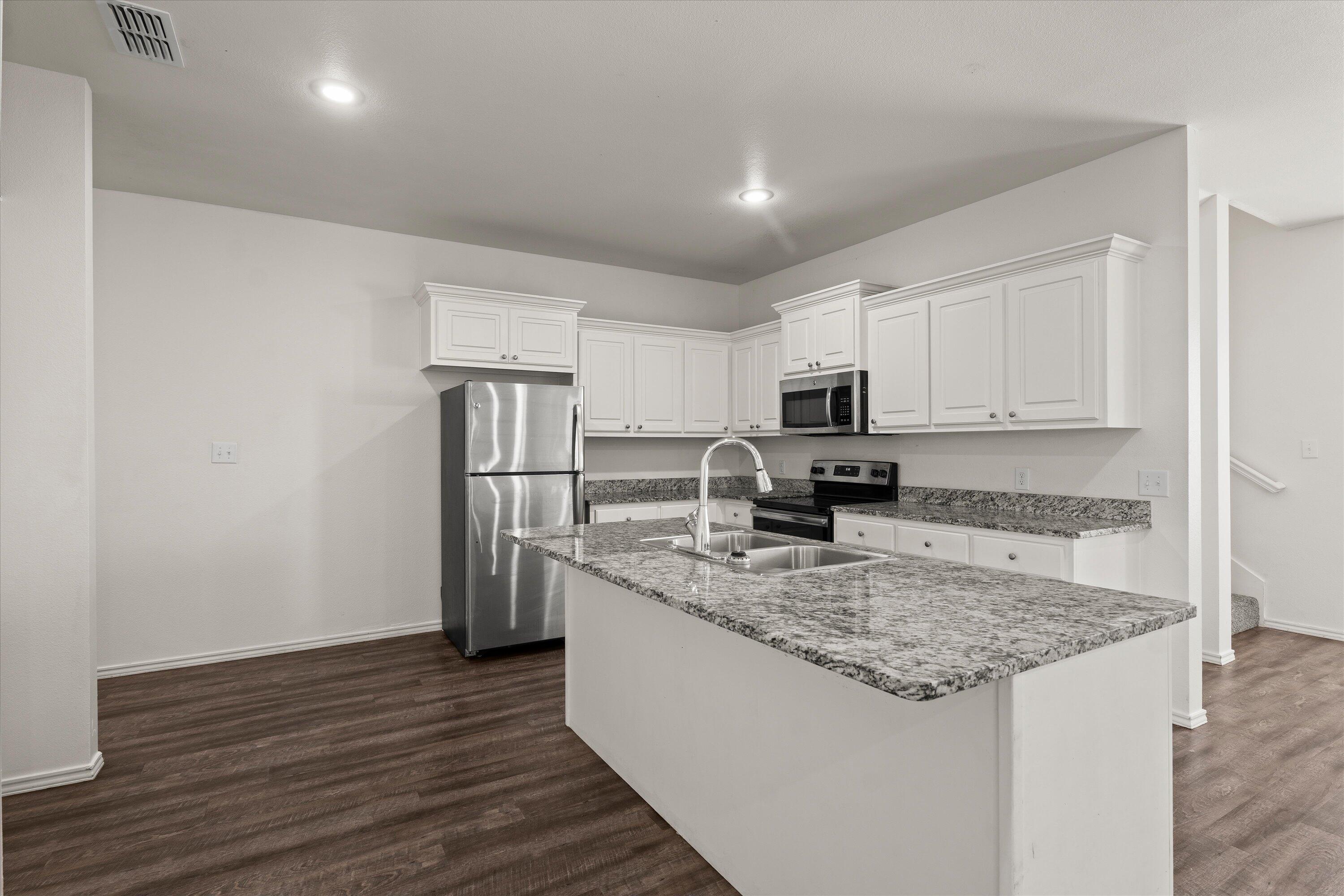 6908 21st Street Lubbock, TX 79407 - Photo 8 of 28 a kitchen with stainless steel appliances granite countertop a refrigerator a stove a sink cabinets and a wooden floor