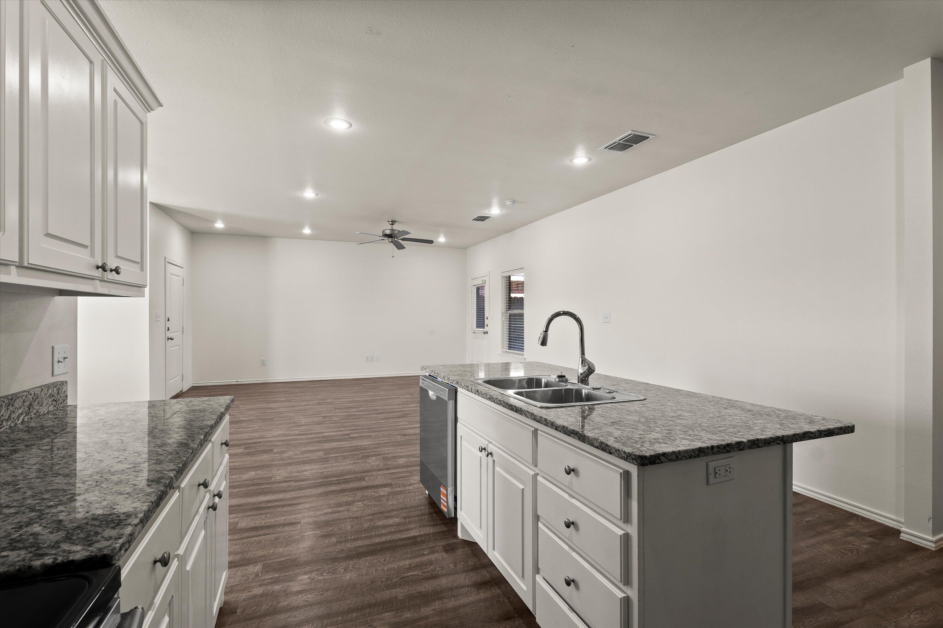 6908 21st Street Lubbock, TX 79407 - Photo 10 of 28 a kitchen with granite countertop a sink and cabinets