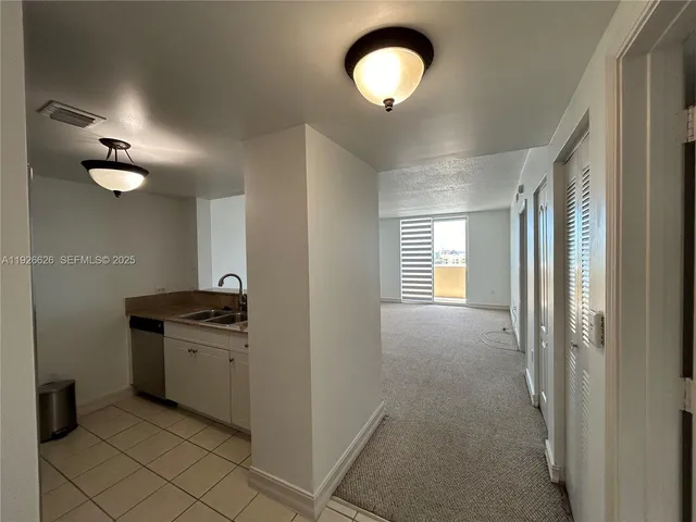 a view of an empty room with a chandelier fan