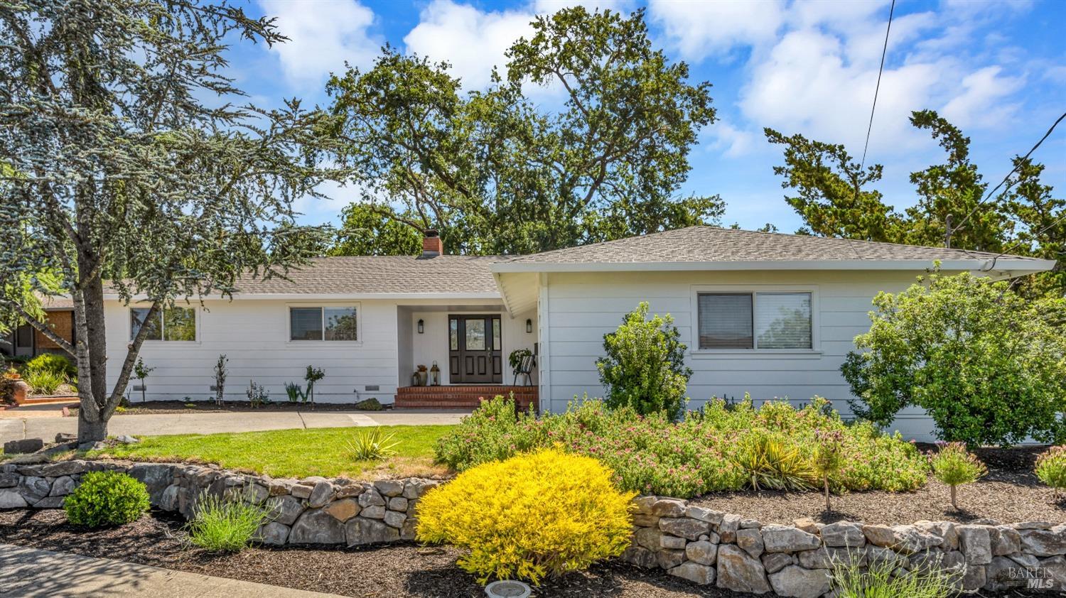 a front view of a house with a yard and potted plants