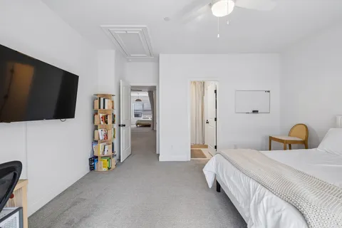 a bedroom with a bed a flat screen tv and a chandelier