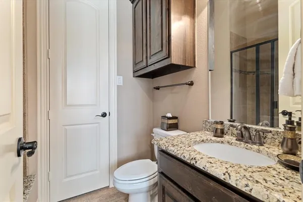 a bathroom with a granite countertop sink a toilet and a mirror