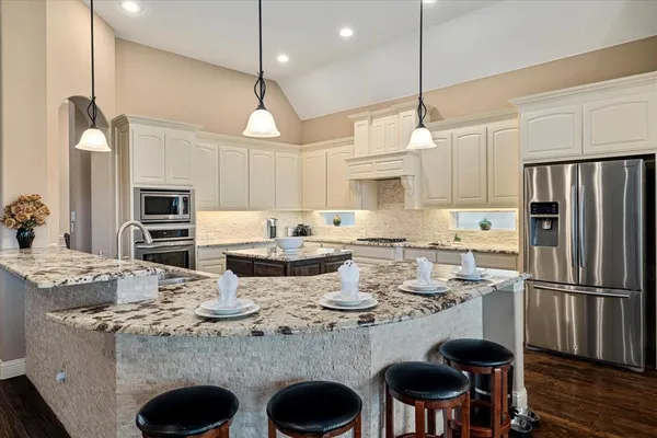 a kitchen with kitchen island granite countertop a table chairs microwave and cabinets