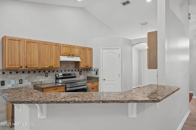 a kitchen with granite countertop a sink a stove and cabinets