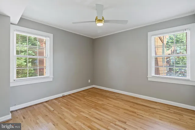 a view of empty room with wooden floor and fan