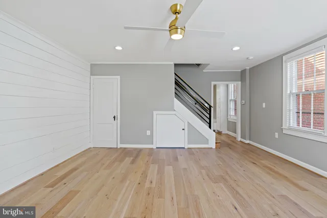 a view of empty room with wooden floor and fan