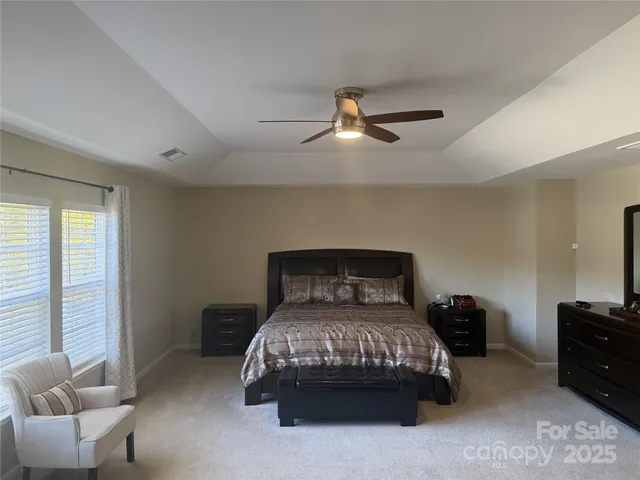 a bedroom with a bed a couch and a ceiling fan