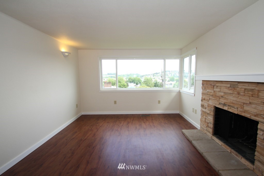 81 Southwest 2nd Street Renton, WA 98057 - Photo 4 of 22 an empty room with wooden floor fireplace and windows