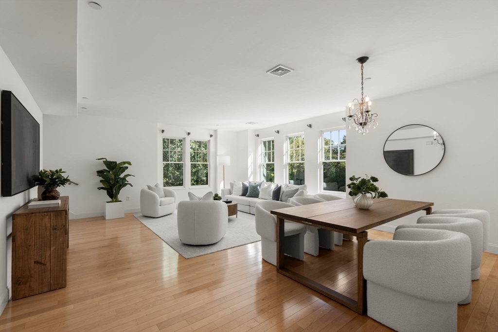 125 Crowninshield Road, Unit 125 Brookline, MA 02446 - Photo 7 of 22 a living room with furniture a window and a chandelier