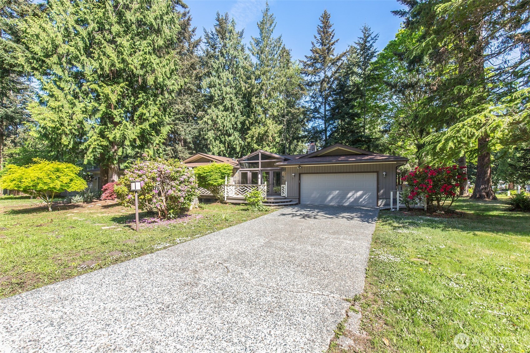 a front view of a house with a garden and trees
