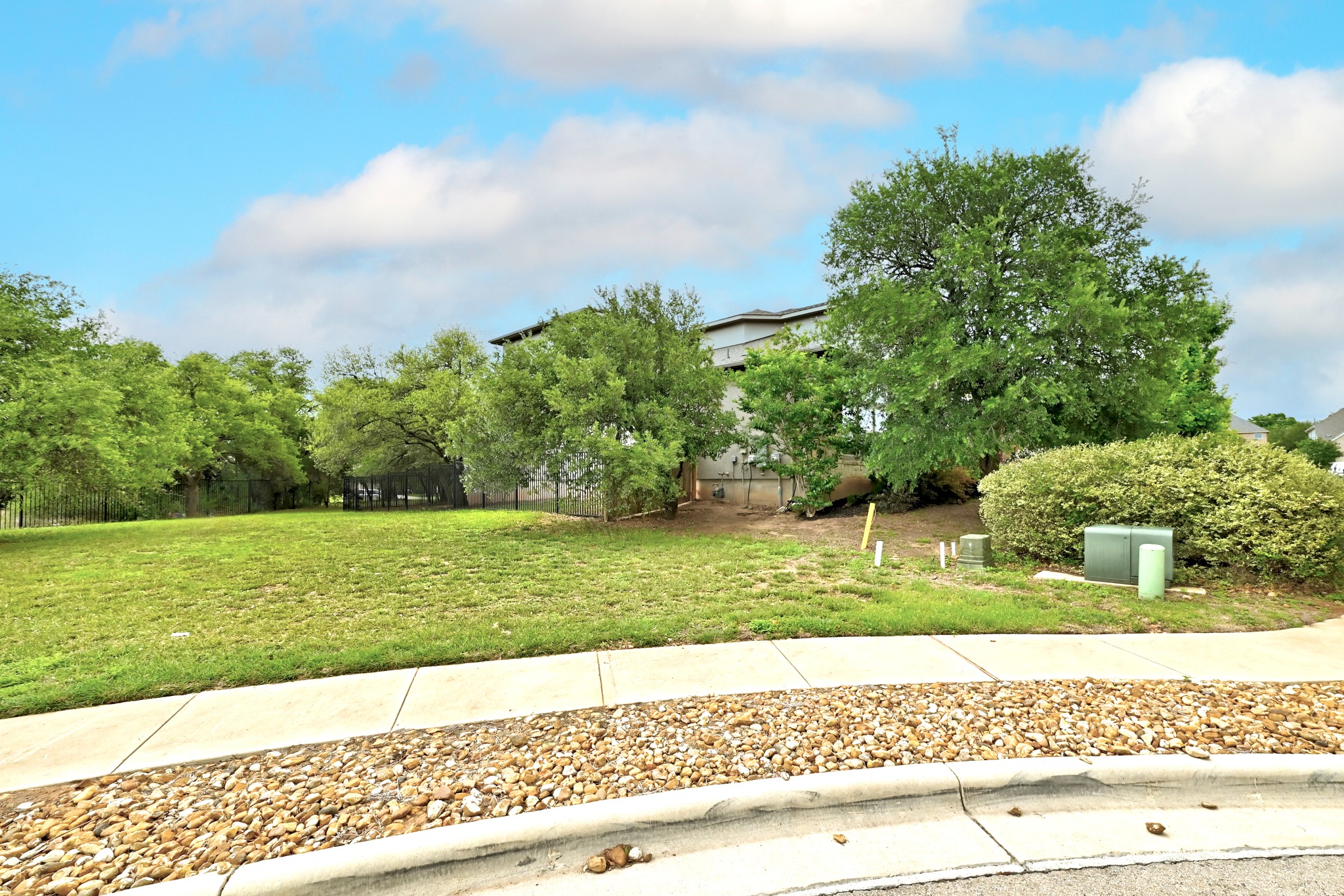 9008 Harper Rae Drive Austin, TX 78717 - Photo 2 of 39 Expansive grassy lot featuring mature trees and a manicured street-side landscape with decorative gravel and a concrete sidewalk