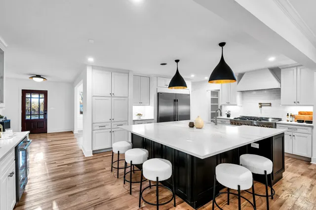 a kitchen with stainless steel appliances a dining table chairs and wooden floor