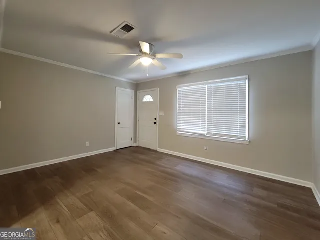 an empty room with wooden floor and windows