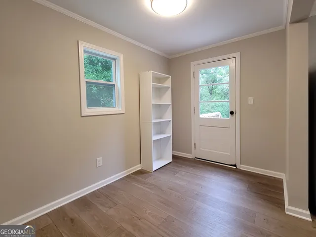 an empty room with wooden floor and windows