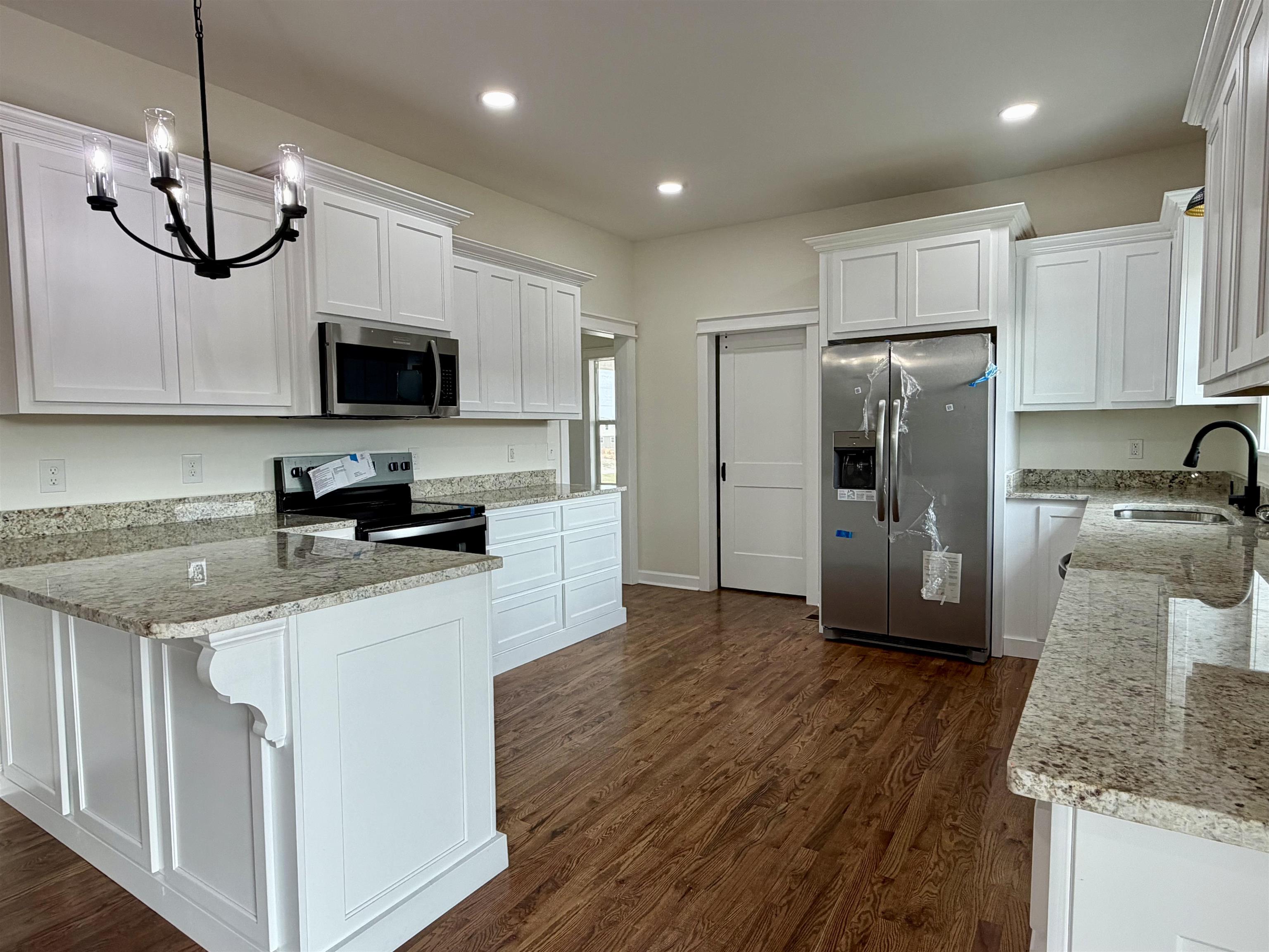 172 New Bethel Road Selmer, TN 38375 - Photo 11 of 30 a kitchen with granite countertop a refrigerator a stove a microwave a sink cabinets and wooden floor