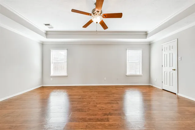 a view of empty room with wooden floor and fan