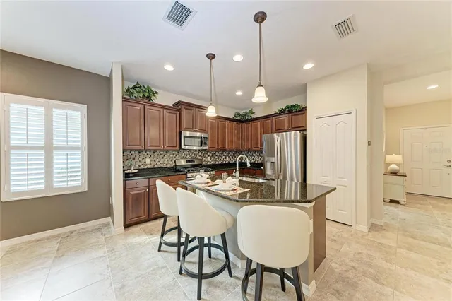 a kitchen with kitchen island a dining table chairs and a refrigerator