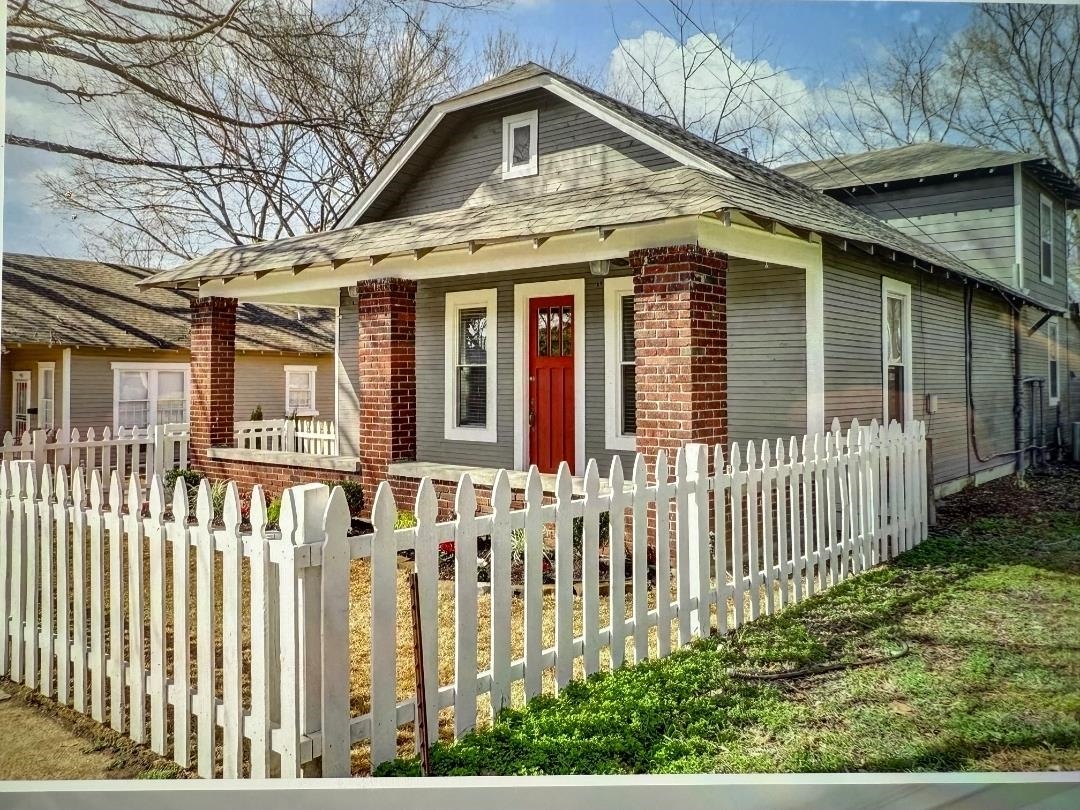 Bungalow with a fenced front yard, covered porch, and roof with shingles