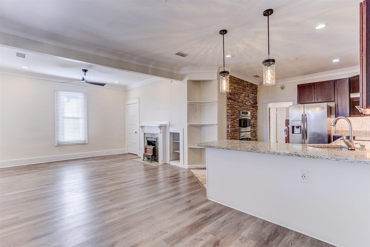 989 Bruce Street Memphis, TN 38104 - Photo 24 of 40 Kitchen featuring light stone countertops, decorative light fixtures, stainless steel appliances, light wood-type flooring, and dark brown cabinetry