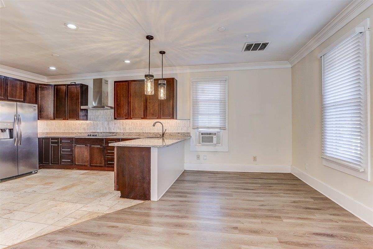989 Bruce Street Memphis, TN 38104 - Photo 28 of 40 Kitchen featuring stainless steel refrigerator with ice dispenser, hanging light fixtures, light wood-type flooring, light stone countertops, and wall chimney range hood