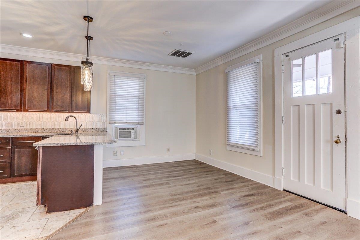 989 Bruce Street Memphis, TN 38104 - Photo 29 of 40 Kitchen featuring hanging light fixtures, light wood-type flooring, dark brown cabinetry, light stone countertops, and crown molding